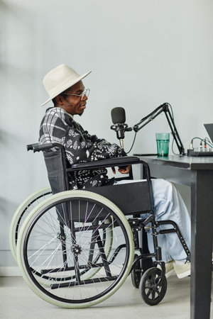 Vertical full length portrait of African-American person in wheelchair giving interview while...