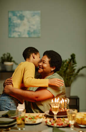 Vertical portrait of happy African-American grandmother embracing boy while celebrating Birthday with familyの写真素材
