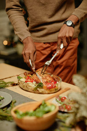 Vertical close up of unrecognizable African-American man serving chicken while enjoying dinner with familyの写真素材