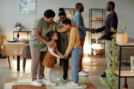 Full length portrait of big African-American family chatting while welcoming guests for dinner party at homeの写真素材