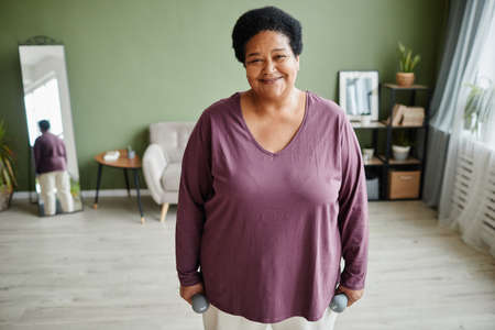 Waist up portrait of black senior woman enjoying workout at home smiling happily, copy spaceの写真素材