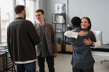 Group of business colleagues embracing and smiling, they greeting each other during meeting at...