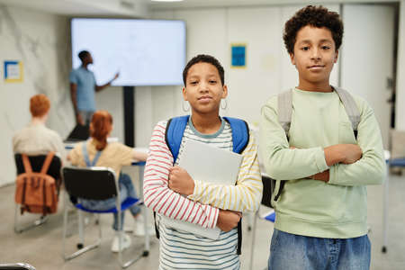 Waist up portrait of two teenage kids looking at camera in school classroom, copy spaceの写真素材