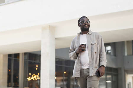 Minimal portrait of smiling black man wearing sunglasses outdoors in city, copy space