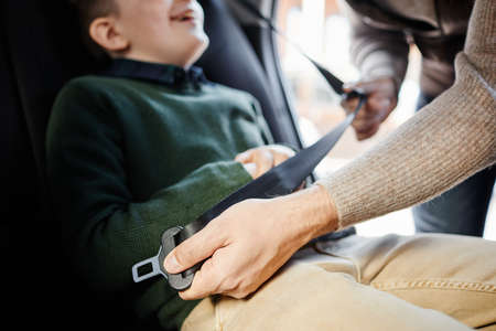 Close up of man buckling son in back seat of family car, copy spaceの写真素材