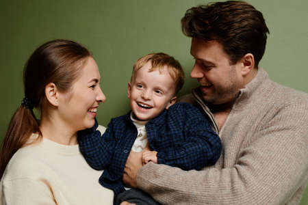 Cozy portrait of loving parents holding little boy and laughing candidの写真素材