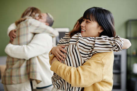 Group of young friends embracing each other during their meeting at homeの写真素材