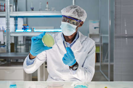 African young scientist in protective wear taking sample during scientific experiment in the...