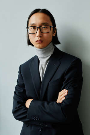 Vertical waist up portrait of successful Asian businessman wearing suit and looking at cameraの写真素材