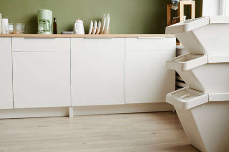 Minimal background image of empty kitchen interior with focus on waste sorting containers in foreground, copy spaceの写真素材