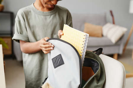 Close up of young African-American boy packing backpack at home, copy spaceの写真素材