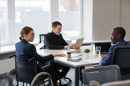 Back view portrait of successful businesswoman using wheelchair while leading board meeting in...