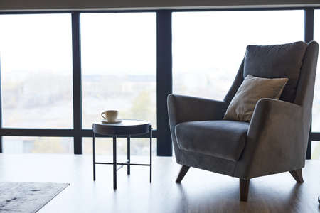 Background image of cozy grey armchair against window in minimal home interior, copy space