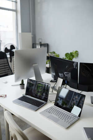 Part of openspace office with group of laptops and computer monitors on workplace of contemporary...