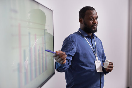 Young confident expert with bottle of vitamins making presentation of financial charts and sales rate of new medicamentsの写真素材