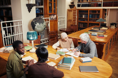High angle portrait of diverse group of people studying at round table in classic college library, copy spaceの写真素材