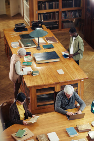 Vertical background of classic library with diverse group of people at wooden table, copy spaceの写真素材