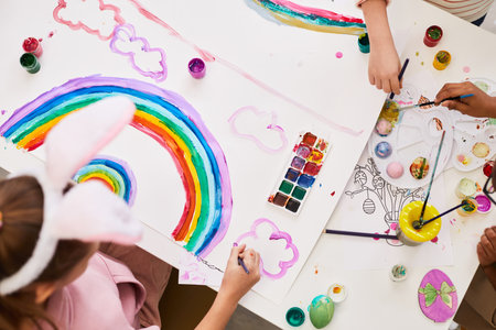 Top view portrait of little girl drawing rainbow at art and craft table while enjoying Easter party for childrenの写真素材