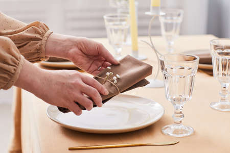 Close up of young woman decorating dinner table in soft Spring tones with dainty flowers and crystal, copy spaceの写真素材