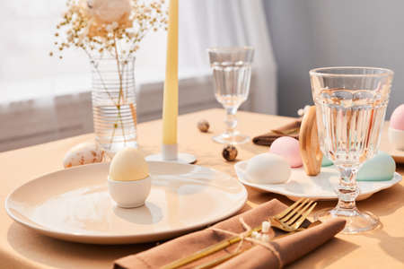 Background image of single Easter egg plated on elegant dinner table decorated for Spring in...