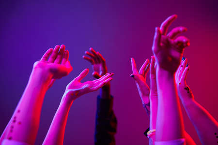 Minimal close up of hands up at party lit by colored lights, group of people dancingの写真素材