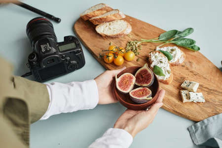 Close up of female food photographer arranging gourmet setup with props in studio, copy spaceの写真素材