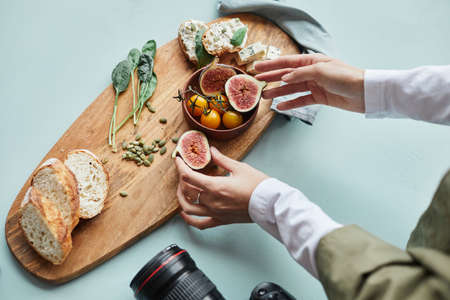 Close up of female food photographer arranging gourmet dish with props while working in studio, copy spaceの写真素材