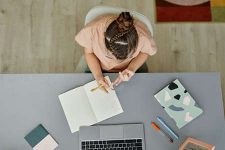 Top view of young girl with down syndrome studying at home while sitting at desk and watching online lesson, copy spaceの写真素材