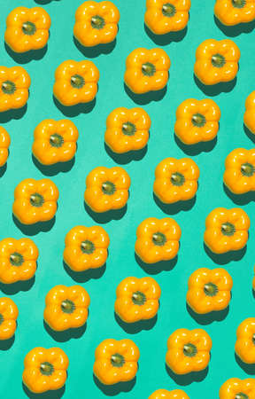 Graphic top view pattern of fresh yellow peppers in diagonal lines on contrasted blue background, healthy eating and vegan concept, copy spaceの写真素材