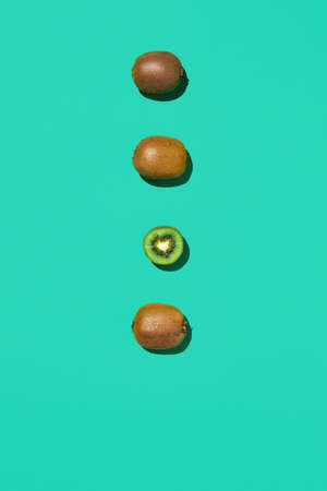 Minimal top view composition of fresh green kiwi fruits in line on vibrant blue background, healthy eating and vegan concept, copy spaceの写真素材