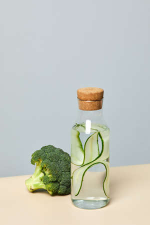 Minimal shot of refreshing cucumber water and broccoli against pastel background, body detox and dieting conceptの写真素材