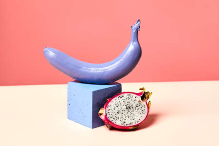 Minimal shot of single purple banana set on podium against pink background with tropical dragon...