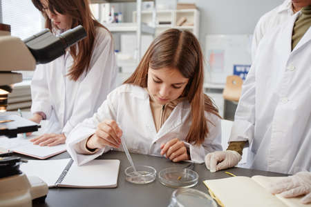 Front view portrait of young girl doing experiments in chemistry lab at school, copy spaceの写真素材