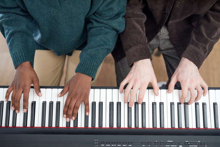High angle view of multiethnic couple playing the synthesizer together during lesson