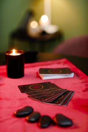 Vertical background image of tarot cards on red velvet table in fortune tellers shop lit by candles, copy spaceの写真素材