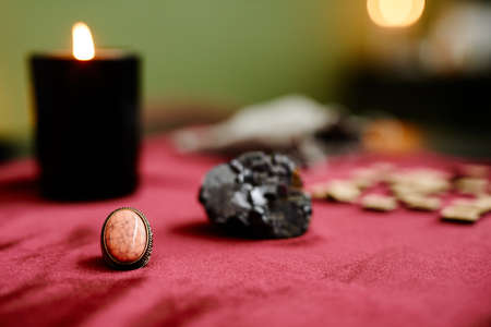 Close up of crystals and spiritual stones on red velvet table with candles in fortune tellers shop, copy spaceの写真素材