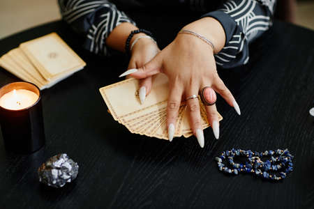 Close up of black woman holding tarot cards over table in fortune tellers shop lit by candles, copy spaceの写真素材