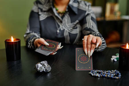 Close up of black woman reading tarot cards at table in fortune tellers shop lit by candles, copy spaceの写真素材