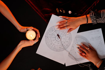 Top view of female fortune teller reading astrology chart for young woman visiting at spiritual seanceの写真素材