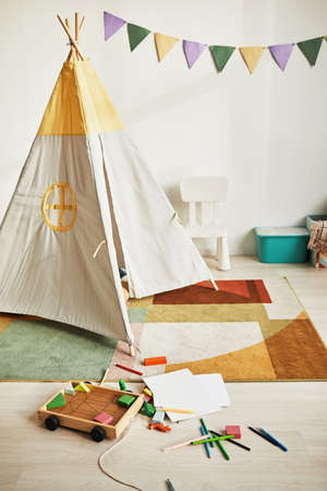 Vertical background image of cute kids room interior with play tent and decor in pastel colors