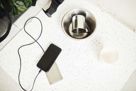 Close up of minimal refugee belongings with smartphone and metal bowl on floor, copy space