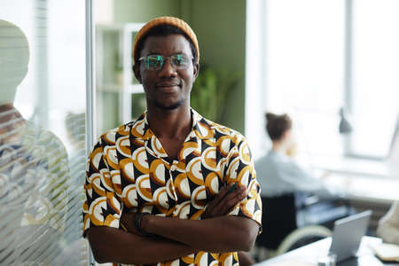 Waist up portrait of black young man wearing bright yellow pattern in office and looking at camera while posing confidently,copy spaceの写真素材