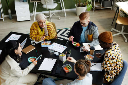 High angle view at diverse creative team at coworking space during lunch