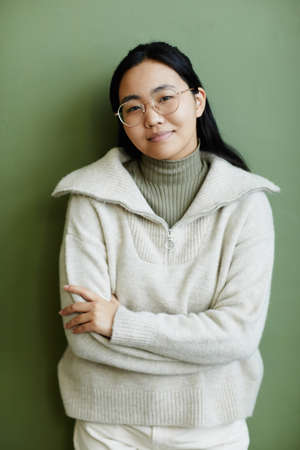 Minimal portrait of Asian young woman wearing comfy knit sweater looking at camera with candid smile