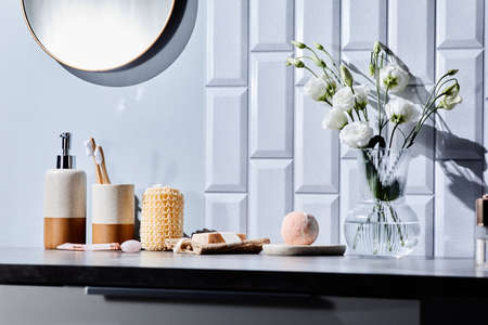 Beauty products for body care with flowers in vase on table in bathroom