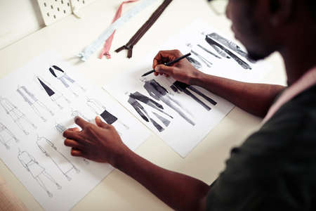 Talented young fashion design student drawing sketches of clothes for his fist collectionの写真素材