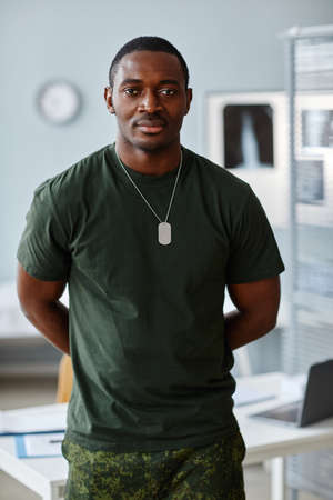 Portrait of handsome young African American military officer standing at doctors office looking at...