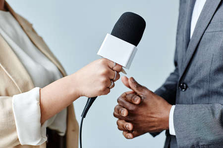 Side view closeup of young woman holding microphone while interviewing business expert