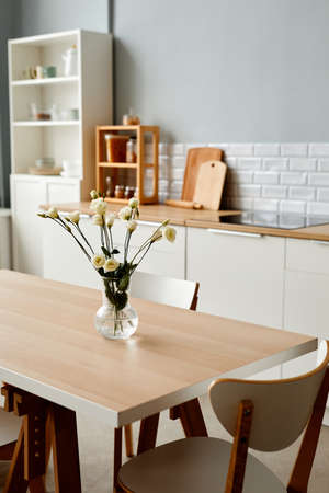 Vertical background image of fresh white flowers on dinner table in minimal kitchen interior, copy spaceの写真素材