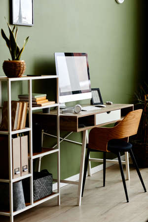 Full length background image of home office workplace with computer on wooden table against green wallの写真素材